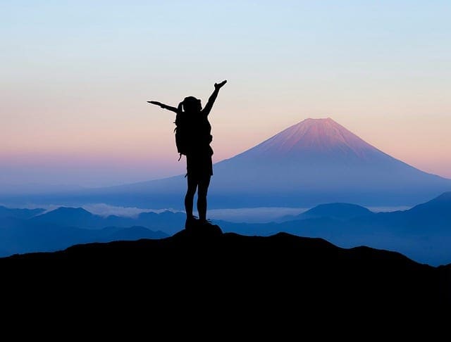 inspirational quotes. A hiker standing on top of a mountain at sunrise.