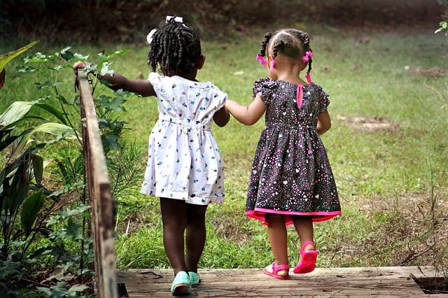 two little girls crossing a bridge holding hands